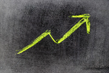 Green chalk draw as upward arrow graph on black board background (Concept for sale, profit, cost of...
