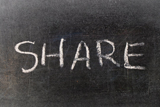 Hand writing by chalk in word share on black board background - Powered by Adobe