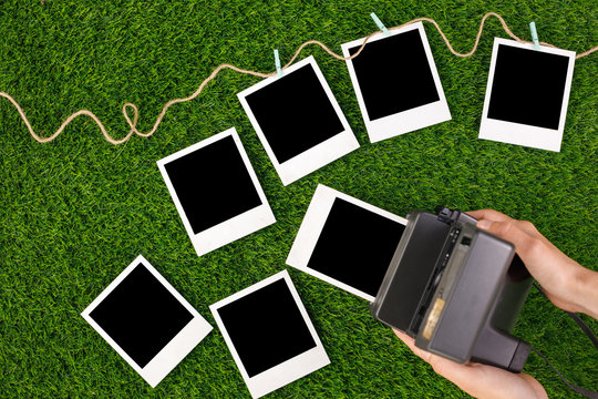 Instant photo frames and a camera on a background of lawn grass. Concept of preservation of memories. Flat lay.