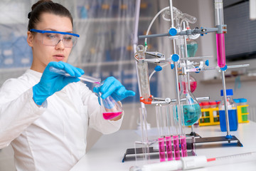 Fototapeta premium Young woman in chemical lab Young woman in chemical lab. cience professional pipetting solution into the glass cuvette.