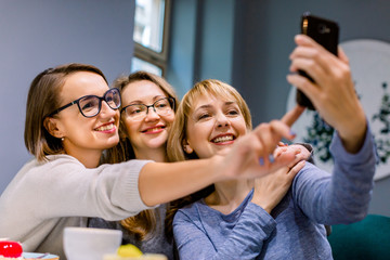 Three beautiful Caucasian women taking selfie in cafe indoors, Meeting of best friends