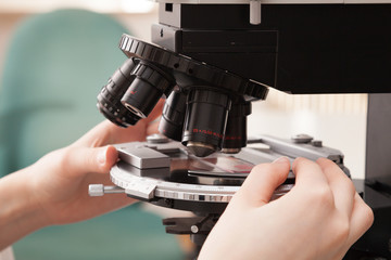 Laboratory assistant uses a polarizing microscope in a microbiological laboratory