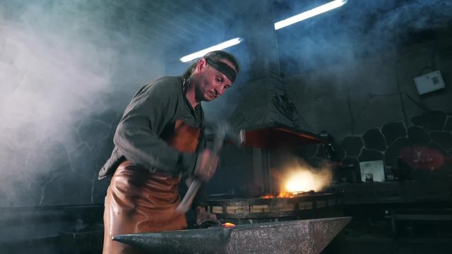 Slow motion of a blacksmith forging incandescent metal