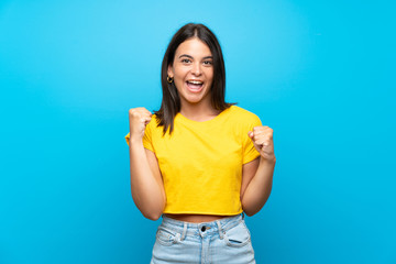 Young girl over isolated blue background celebrating a victory in winner position