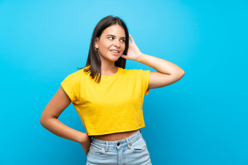 Young girl over isolated blue background listening to something by putting hand on the ear