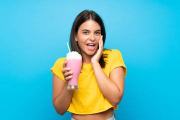 Young girl with strawberry milkshake over isolated background with surprise and shocked facial expression