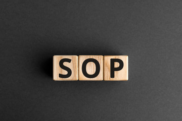 SOP - acronym from wooden blocks with letters, abbreviation SOP standard operating procedure concept, gray background