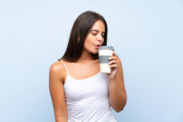 Young woman holding a take away coffee over isolated blue background