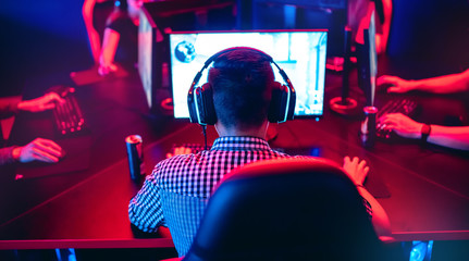 Professional gamer playing online games tournaments pc computer with headphones, Blurred red and...