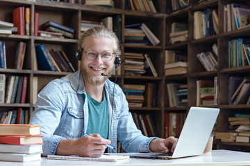 Happy smiling young man student wear headset using laptop computer for e learning course online...