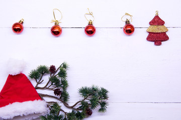 Christmas background top view. Christmas decorations around the perimeter of red and gold. Coniferous tree branches with New Year's toys on a background of a white wooden board. New Year 2020