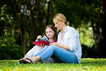 Fototapeta premium Mother and son are reading a book and smile at the park