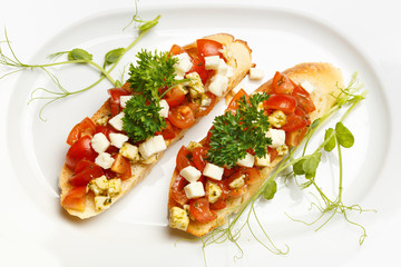 Bruschetta with mozzarella cheese and cherry tomatoes on a white plate