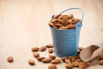 Almonds in blue bucket. on wooden table. Almond concept with copyspace.