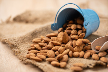 Almonds pour from blue bucket. on wooden table. Almond concept with copyspace.