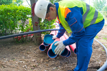 worker in protective uniform, inserts a cap into plastic pipes, to protect from water