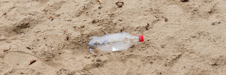 Discarded plastic water bottle lies in the sand on a beach