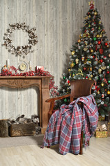 Fototapeta na wymiar Beautiful Christmas interior in brown tones with a Christmas tree, a fireplace made of wood and a chair with a plaid