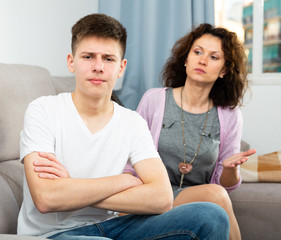 Frowning teenager listening to reprimanding from mother