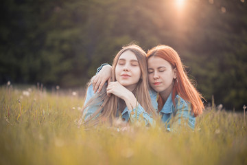 Two girls lie on the grass. Best friends. Eyes closed