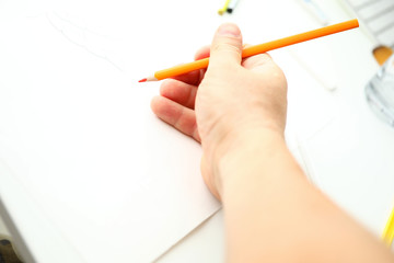 Male hand holding orange pencil ready to draw