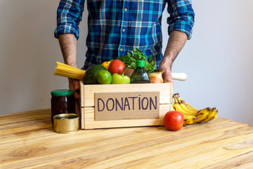 Food donation concept. A man holding a donation box with vegetables, fruits and other food for donation