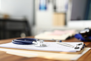 Stethoscope head lying at worktable over patient medical history