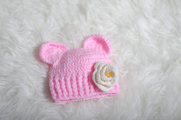 Cute children's knitted hat with ears like a mouse on a white carpet, close-up