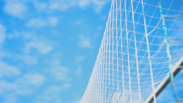 Soccer ball in goal net against blue sky.