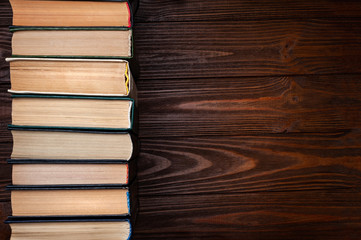 Old books . Group of old used hardcover closed books in dust on a dark wooden background with space for text.