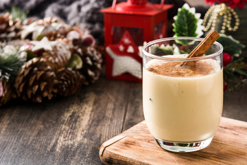 Homemade eggnog with cinnamon in glass on wooden table. Typical Christmas dessert. Copy space