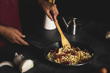 Close-up person making pasta in pan