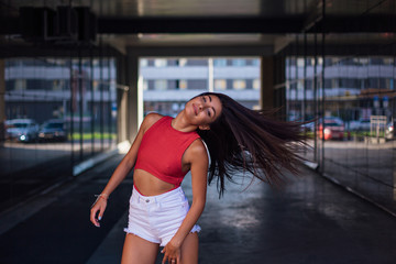 Young brunette woman dancing and shaking her hair in arch of building.