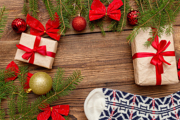 Fur spruce pine coniferous branches, home, house, gift box craft paper with red bow, red gold toys balls on the brown brushed wooden background close up