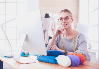 Fashion designer woman working in studio, sitting at thhe desk