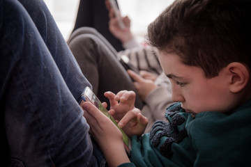 Un jeune garçon regardant un smartphone. Un enfant avec un téléphone portable. Un enfant sur les...