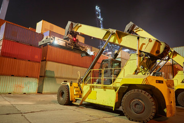 reach stacker puts container in stack. industrial port with containers