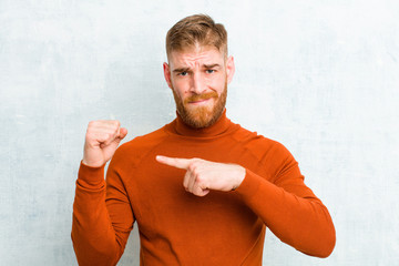 young red head man wearing turtle neck looking impatient and angry, pointing at watch, asking for...