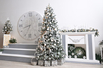 Beautiful Christmas light interior with a snow-covered Christmas tree by the fireplace and a large...