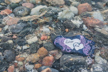 Love first, a stone with an inscription in the water among the waves
