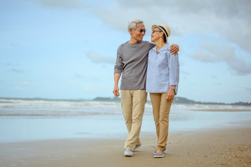 Senior couples embrace the sunrise beach, plan life insurance with the concept of happy retirement.