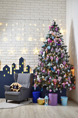 Interior of a children's playroom decorated for the New Year holiday, with a Christmas tree, an armchair and soft toys, against a white brick wall.