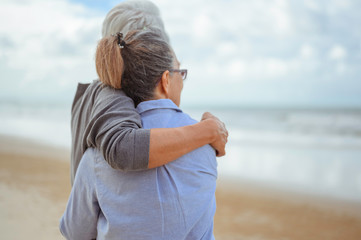 A senior couples embrace the beach in the morning, look at the bright blue skies and plan life...