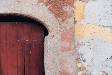 une vieille porte rouge en bois et un vieux mur décrépi