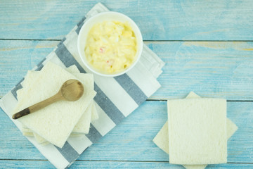 Boiled egg mixed with mayonnaise salad cream in bowl with white bread.