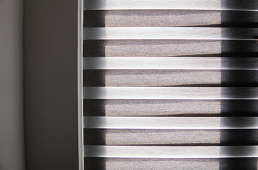 Details of brown fabric roller blinds on the plastic window with wood texture in the living room.