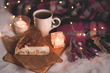 Obraz na płótnie Canvas Winter pie with fresh cup of tea and burning candle in bed close up. Evening time.
