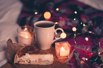 Cup of coffee with tsaty pie and burning candles in room. Evening time. Winter season.