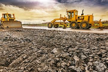 Excavator to level and smooth the land in the construction of a road - obrazy, fototapety, plakaty