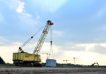 Crawler crane on the construction site for loading and unloading and construction works. Heavy industrial machinery on the background of a sunset